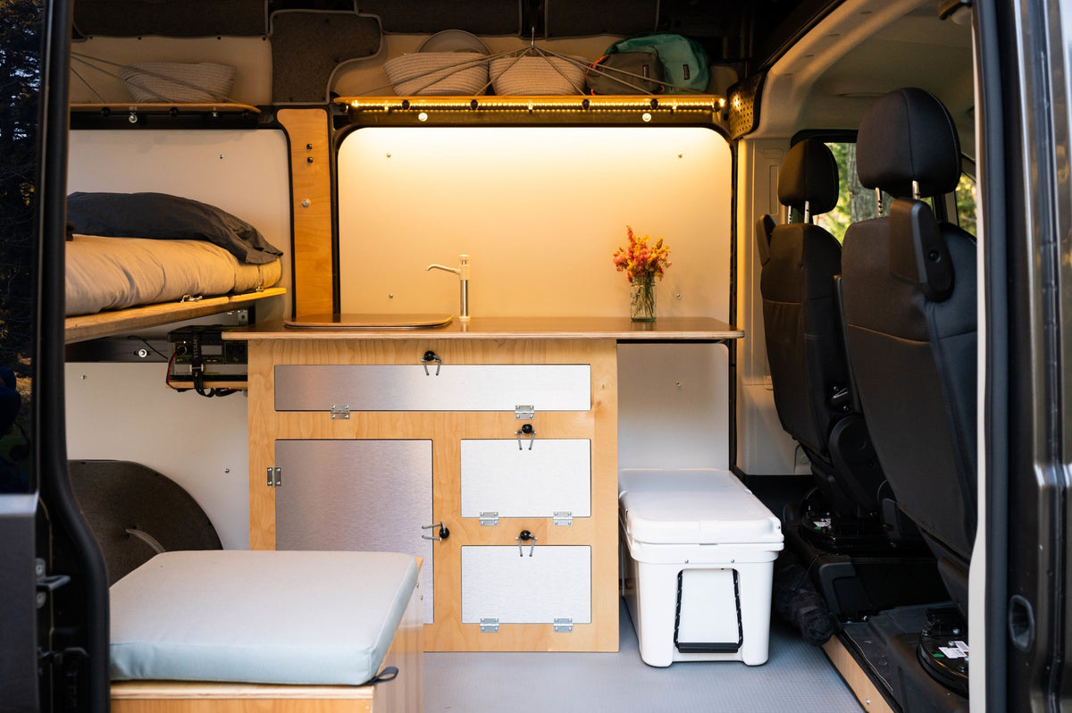 Inside this RV rental camper van: a cozy bed, kitchenette with sink, smart storage, power station, & cooler for ultimate comfort. — photo 10