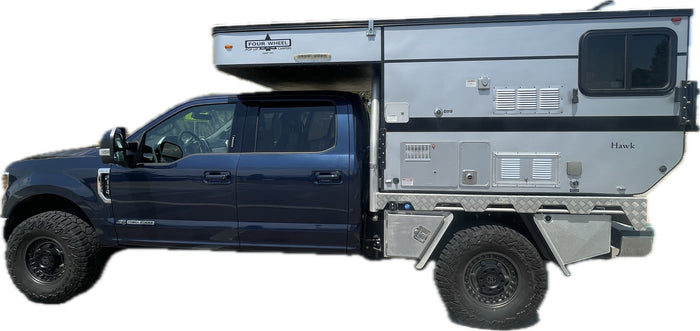 depicted by a logo of antlers & a pine tree. Inquire for booking.|Dark blue Ford truck with off-road tires and a Four Wheel Hawk pop-up truck camper