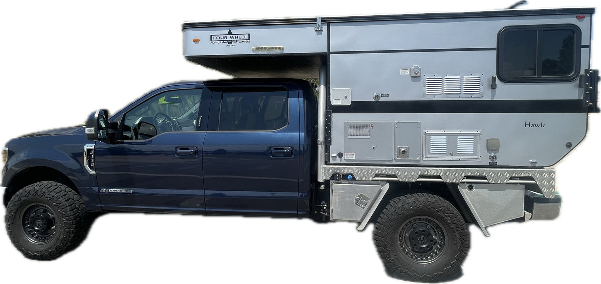 depicted by a logo of antlers & a pine tree. Inquire for booking.|Dark blue Ford truck with off-road tires and a Four Wheel Hawk pop-up truck camper — photo 2