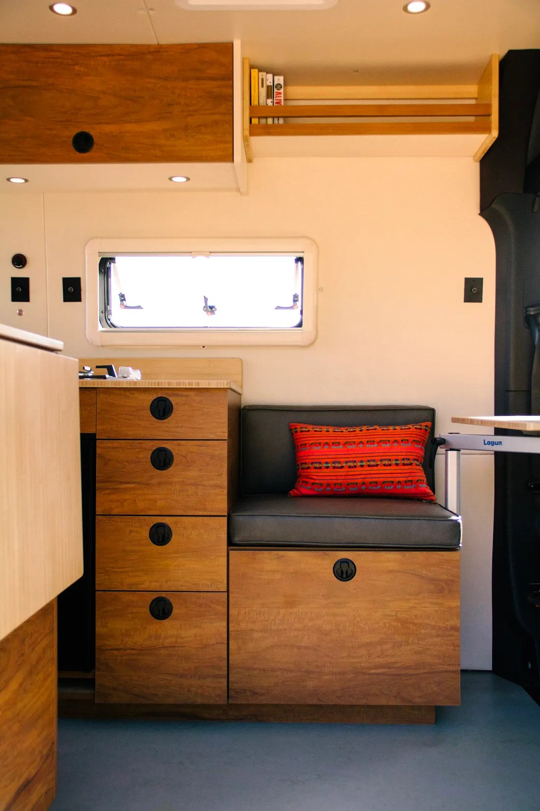 her dog watches below. Perfect for your next outdoor adventure or road trip.|This rv rental camper van boasts warm wood cabinetry — photo 3
