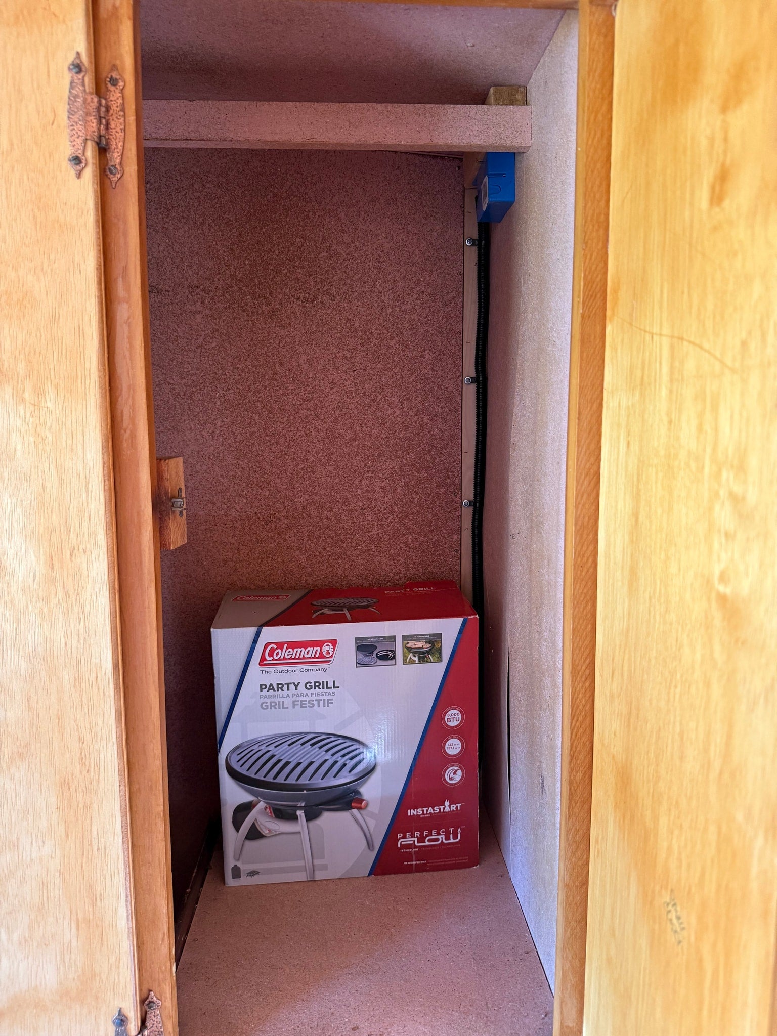 RV rental storage: A Coleman Party Grill box neatly fits in a compact cabinet, ideal for outdoor cooking on the go.