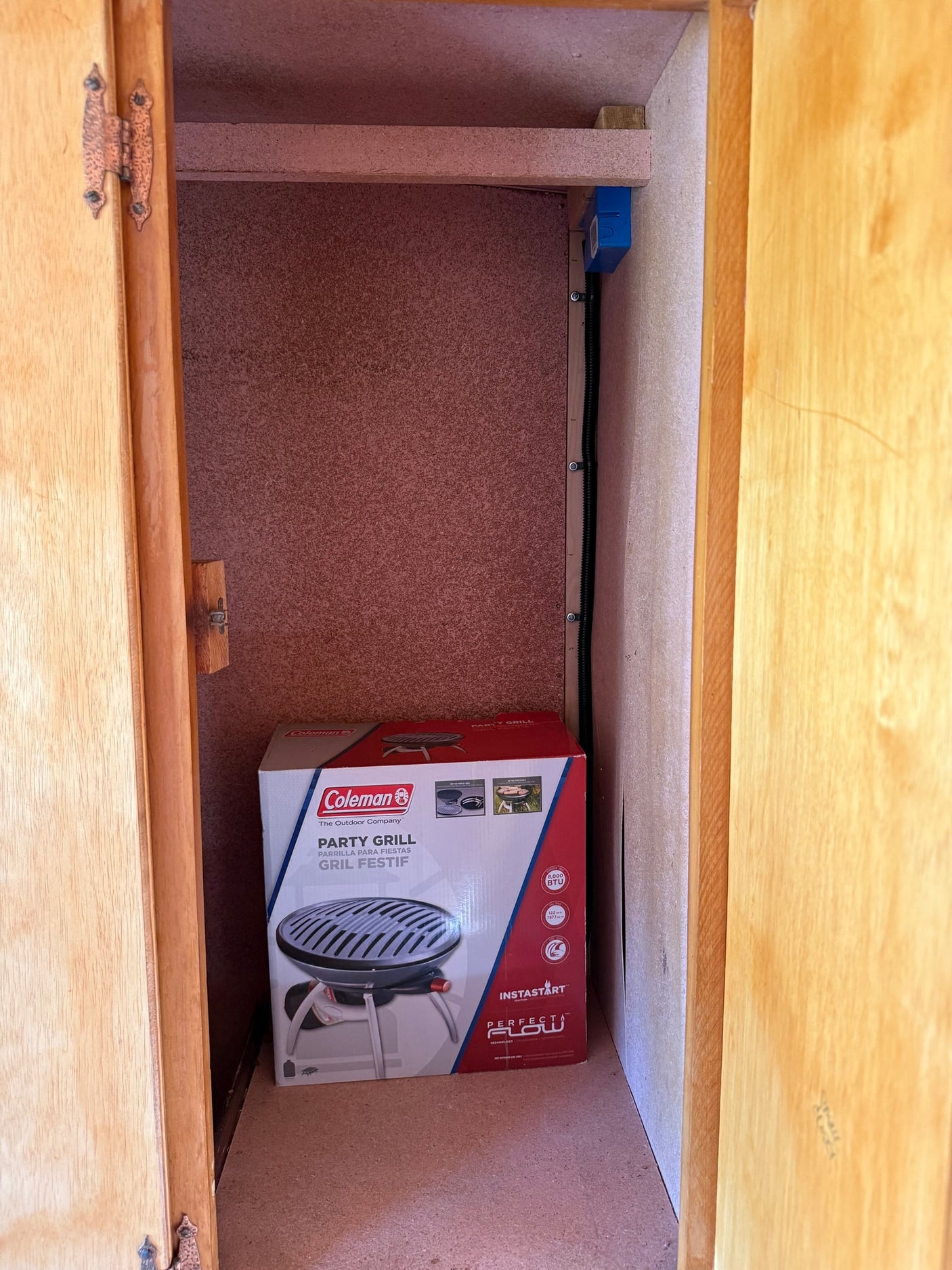 RV rental storage: A Coleman Party Grill box neatly fits in a compact cabinet, ideal for outdoor cooking on the go.
