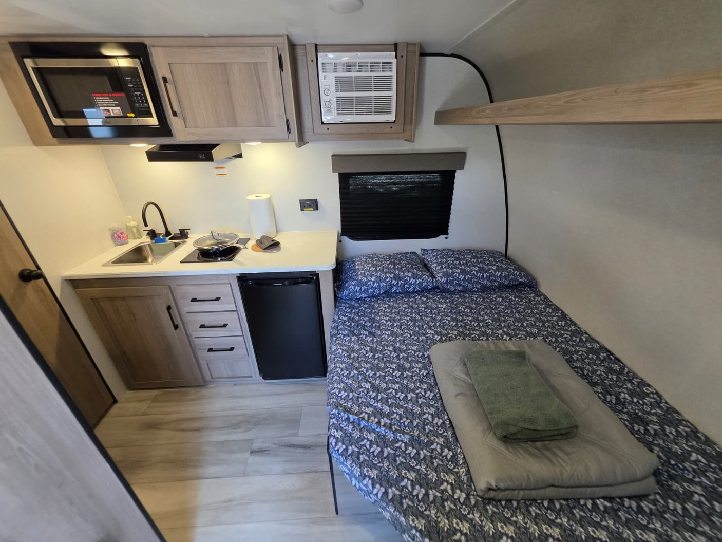 and an open cabinet revealing a trash can and cleaning supplies.|**RV rental** kitchen storage: neatly stacked plates