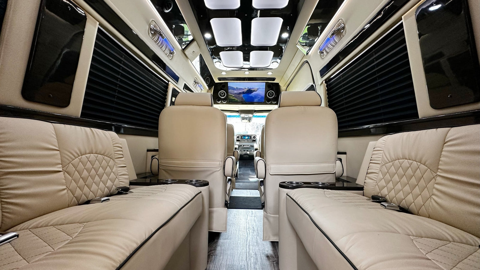 Step inside this luxury RV rental interior: plush cream seating, a flat-screen TV, and ambient lighting create comfort.