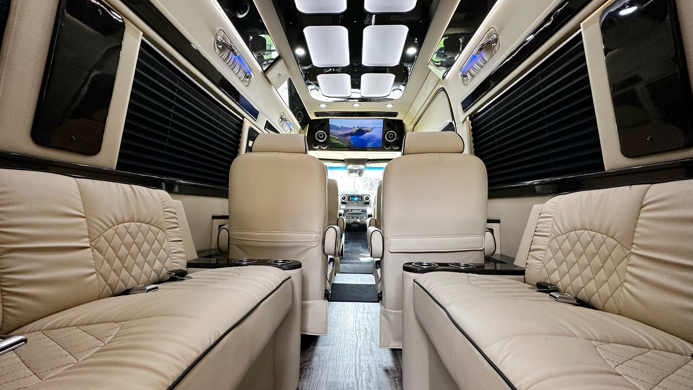 Step inside this luxury RV rental interior: plush cream seating, a flat-screen TV, and ambient lighting create comfort.
