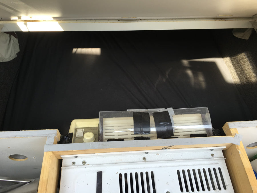 RV rental interior with a portable AC unit at the foot of the bed, illuminated by sunlight from above.