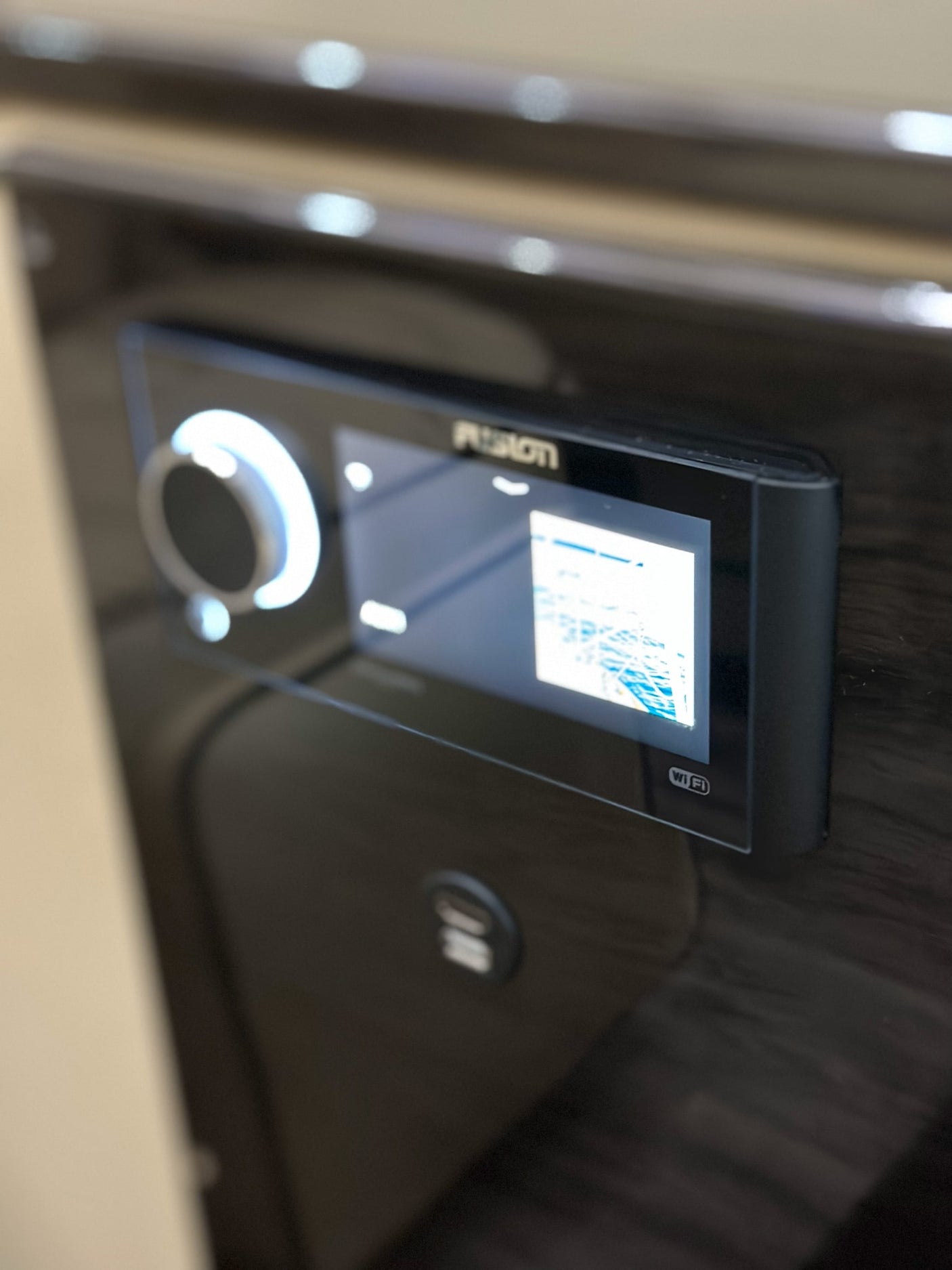 An RV rental control panel: a Fusion stereo with illuminated knob, digital screen, and USB port, built into a dark surface.
