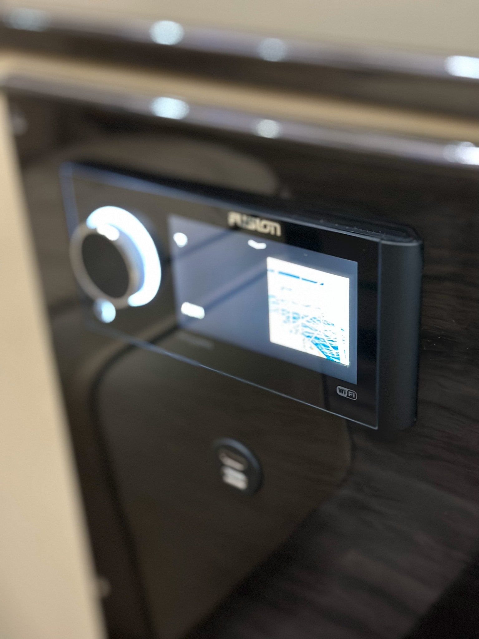 An RV rental control panel: a Fusion stereo with illuminated knob, digital screen, and USB port, built into a dark surface.