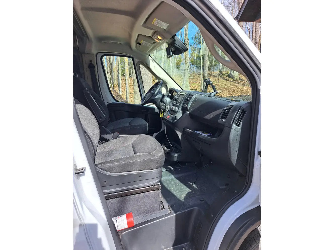 Front cabin of an RV rental van, showcasing driver/passenger seats, dashboard, and a visible fire extinguisher.