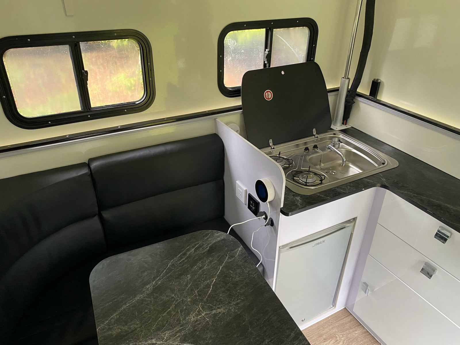 and white cabinets.|This RV rental interior shows a compact kitchen with stove/sink