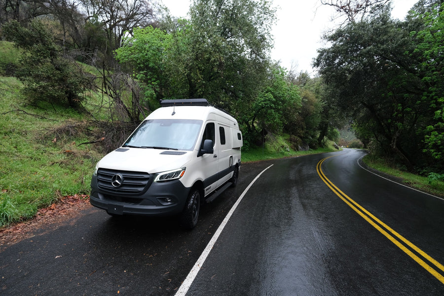 and a dry riverbed.|A deer stands wet in a rainy meadow with pink flowers. See nature up close on your next RV rental adventure!|White Mercedes-Benz Sprinter camper van rv rental parked on a wet