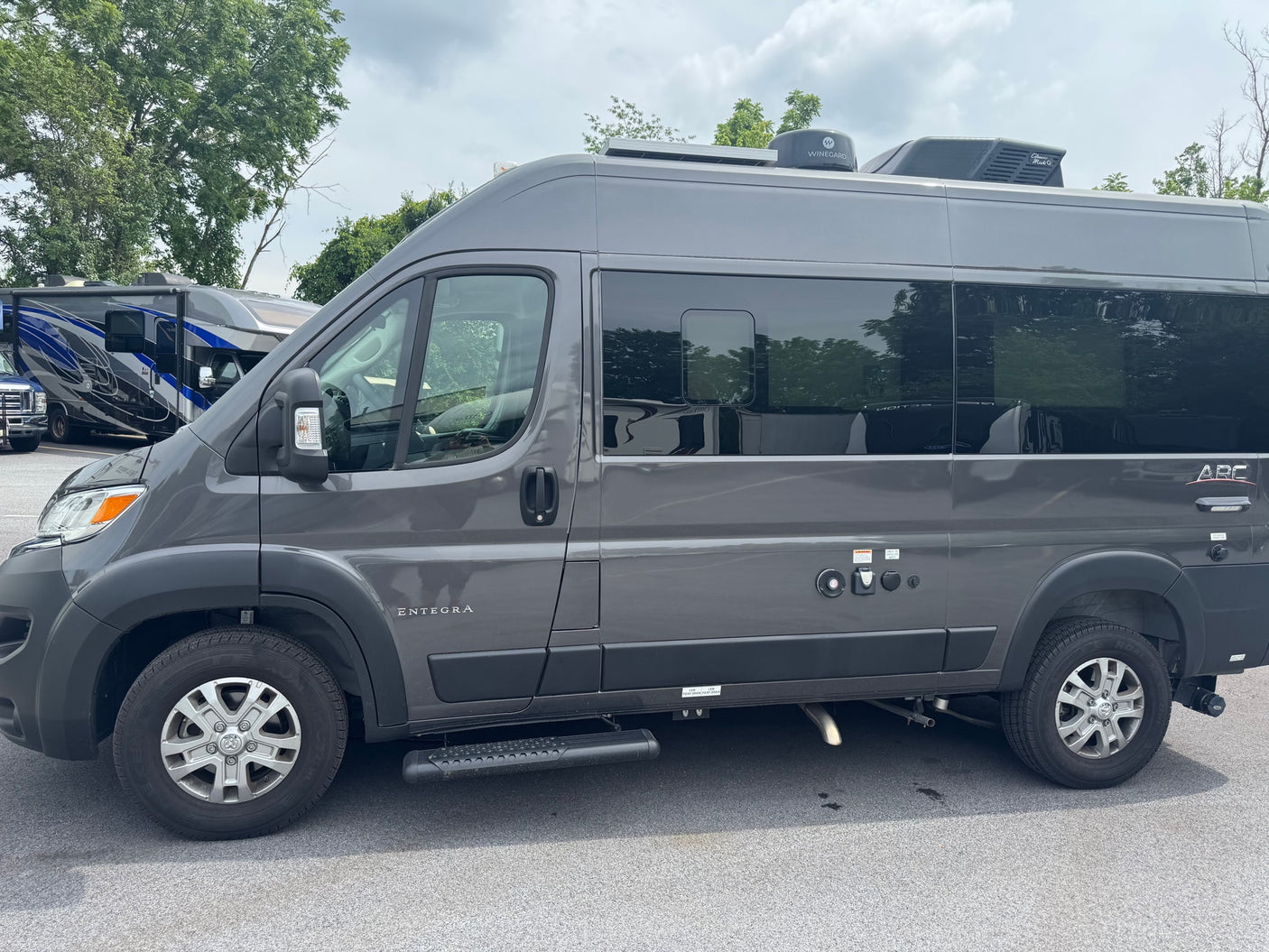 This dark grey Entegra Arc camper van, ideal for RV rental adventures, features a roof AC and Winegard satellite dish.