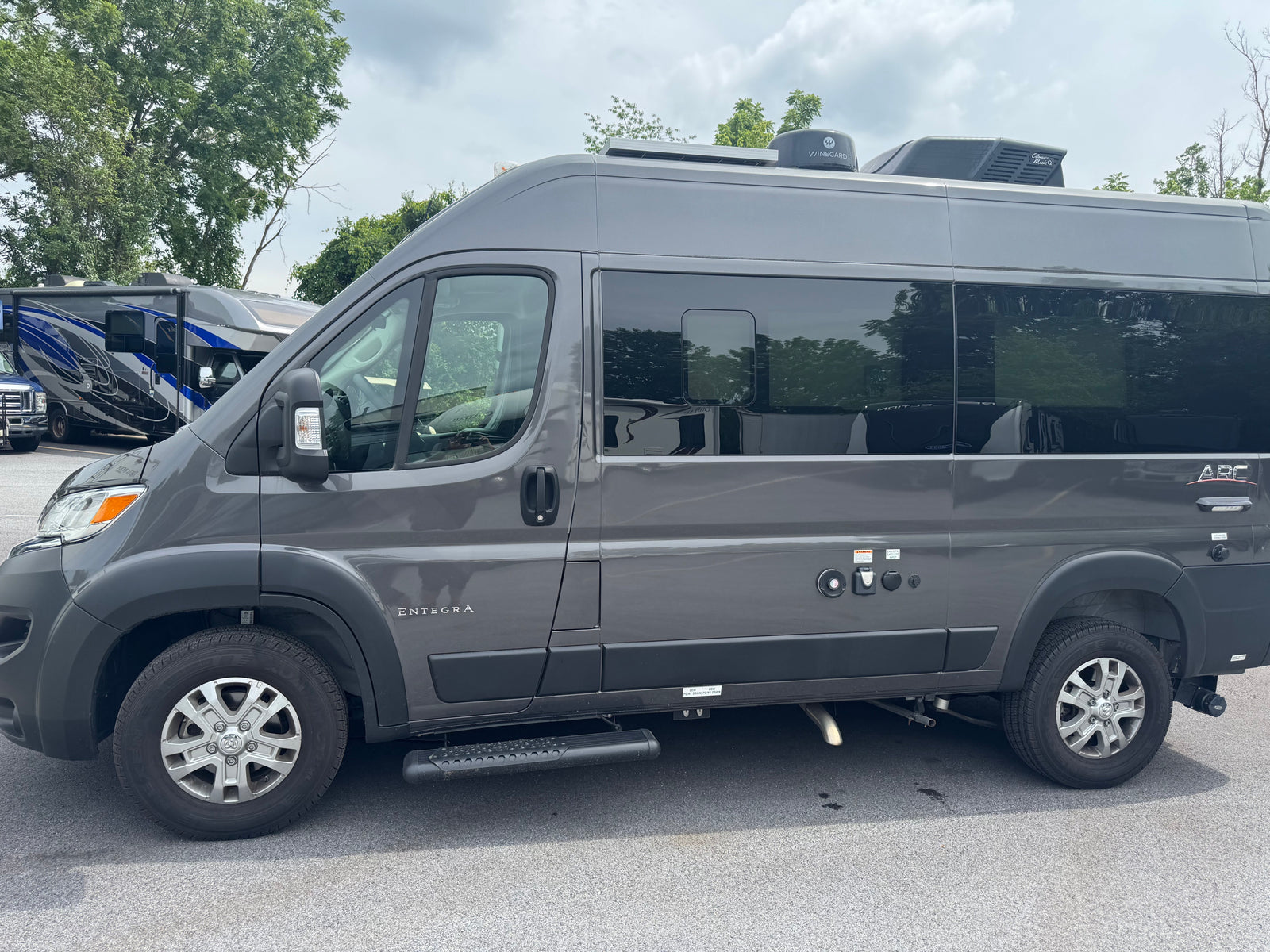 This dark grey Entegra Arc camper van, ideal for RV rental adventures, features a roof AC and Winegard satellite dish.