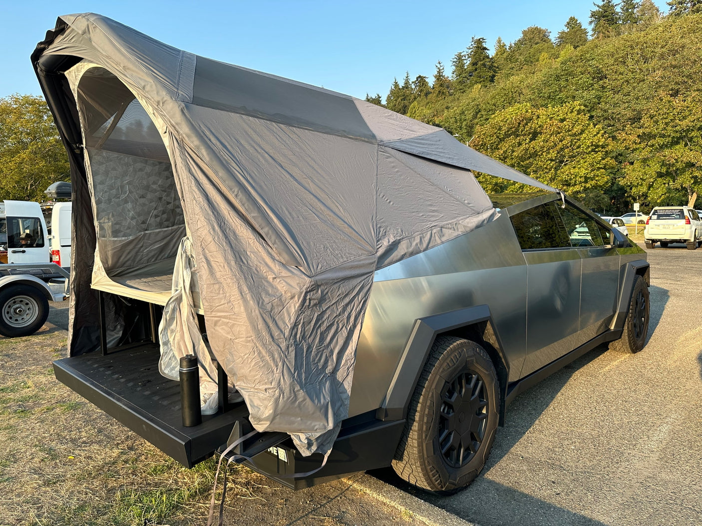 An electric Tesla Cybertruck with an attached overlanding tent setup, offering a modern RV rental alternative for adventures.