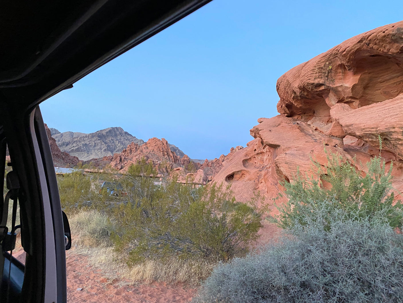 View from RV rental: striking red rocks and desert flora under a clear sky.