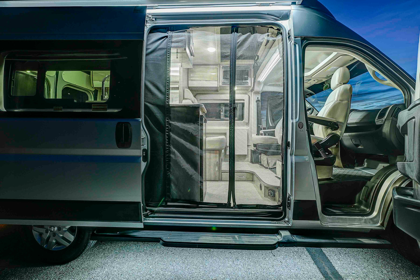 Modern RV rental camper van with open side door, showing the inviting interior living space and driver's cabin.