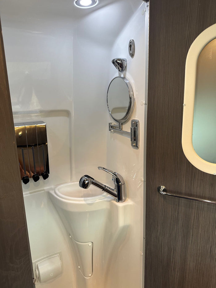 showing a convertible black bench bed and storage space.|Compact rv rental wet bath featuring a sink