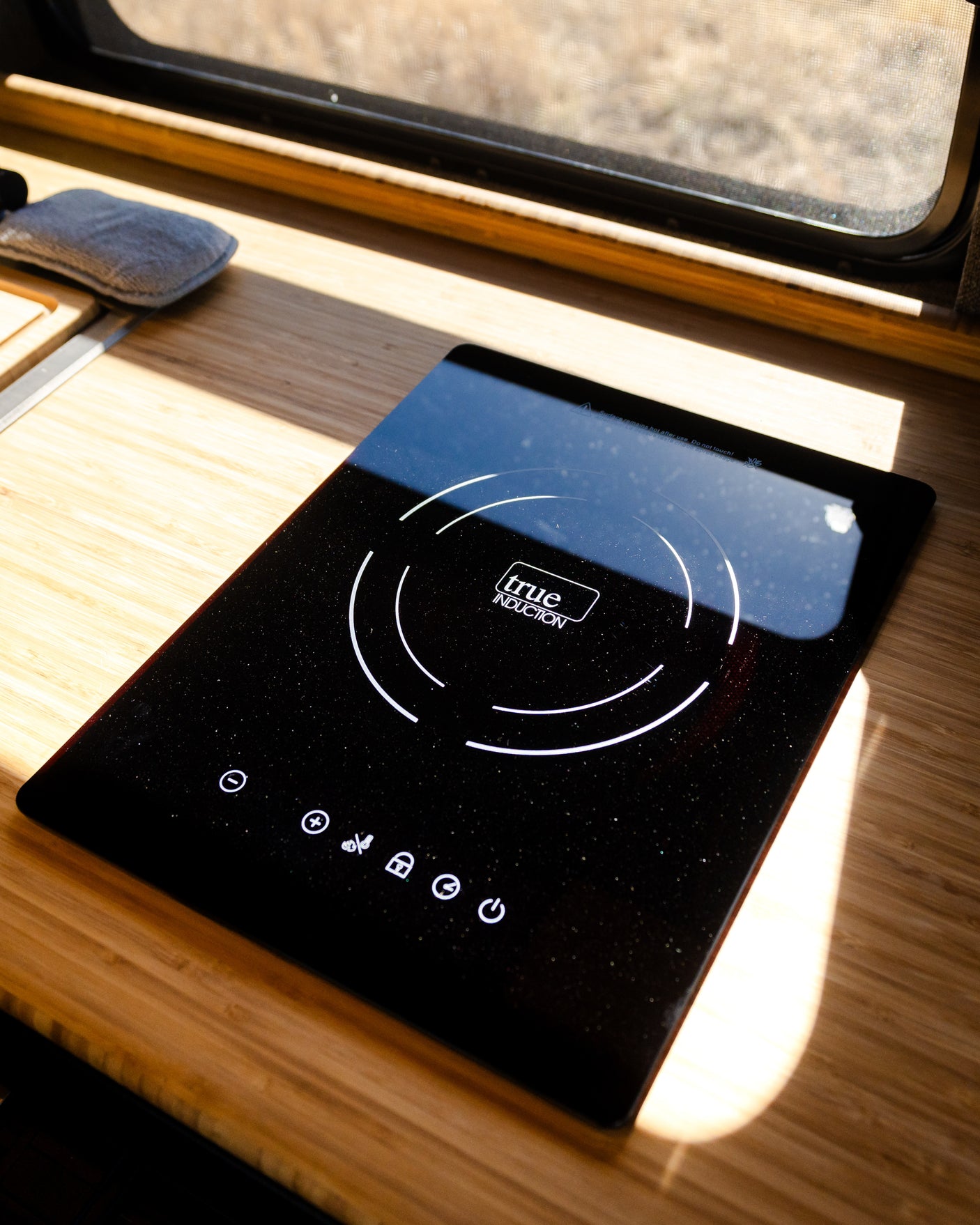 Sleek induction cooktop in an RV rental, set on a bright wooden counter. Ideal for camper kitchen cooking.