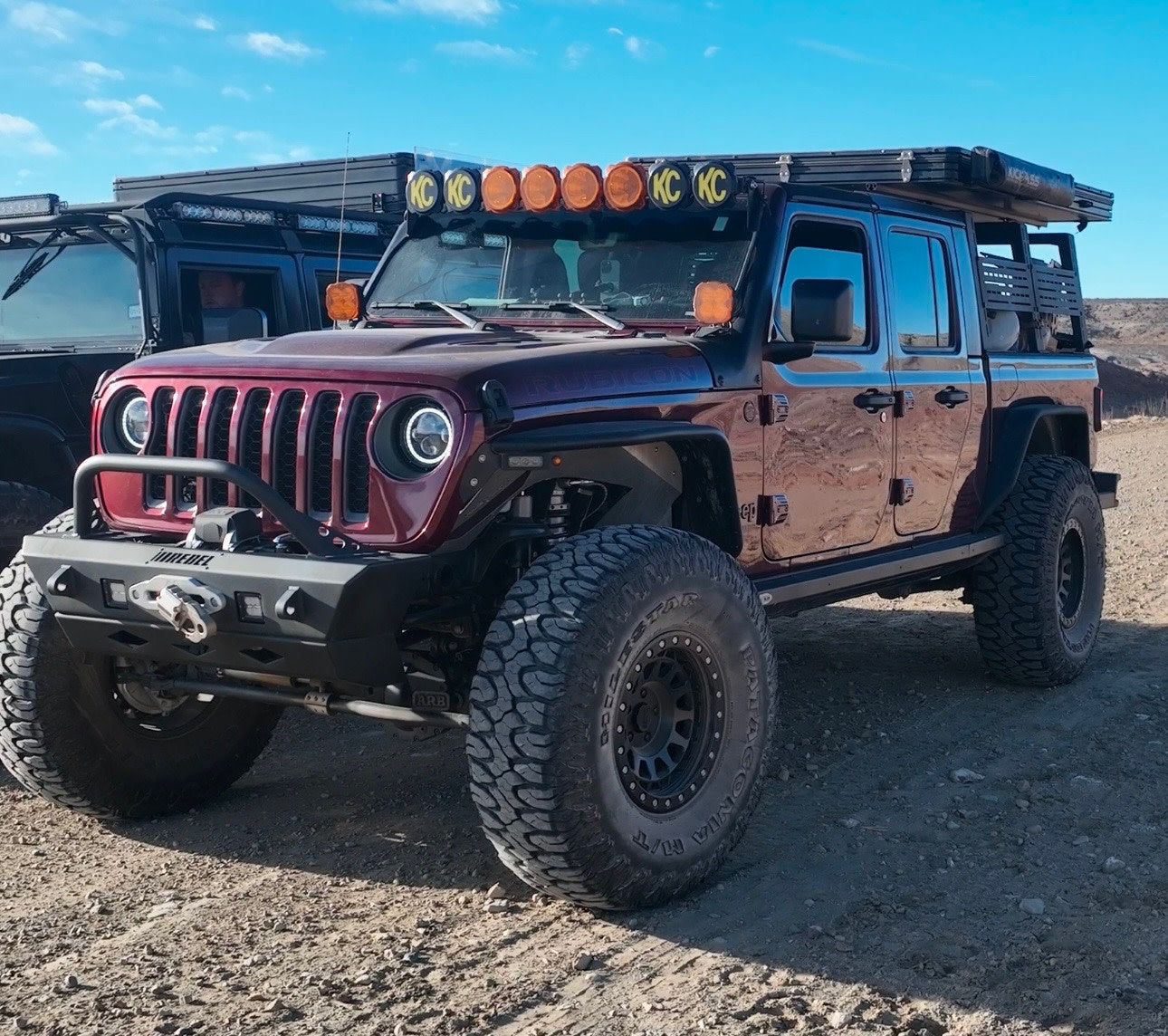 Custom red Jeep Gladiator off-road rig with roof tent