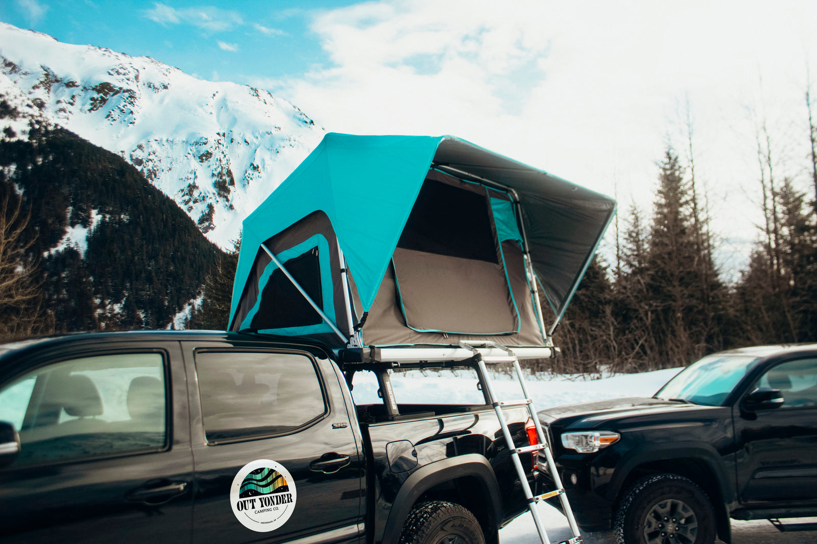 Explore with our RV rental alternative: a truck with a deployed teal rooftop tent, ready for mountain camping.