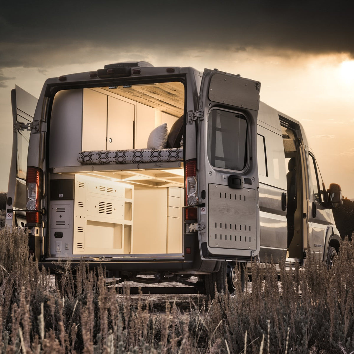 with sun rays peeking over the horizon.|This RV rental camper van showcases a comfortable interior with bed & storage
