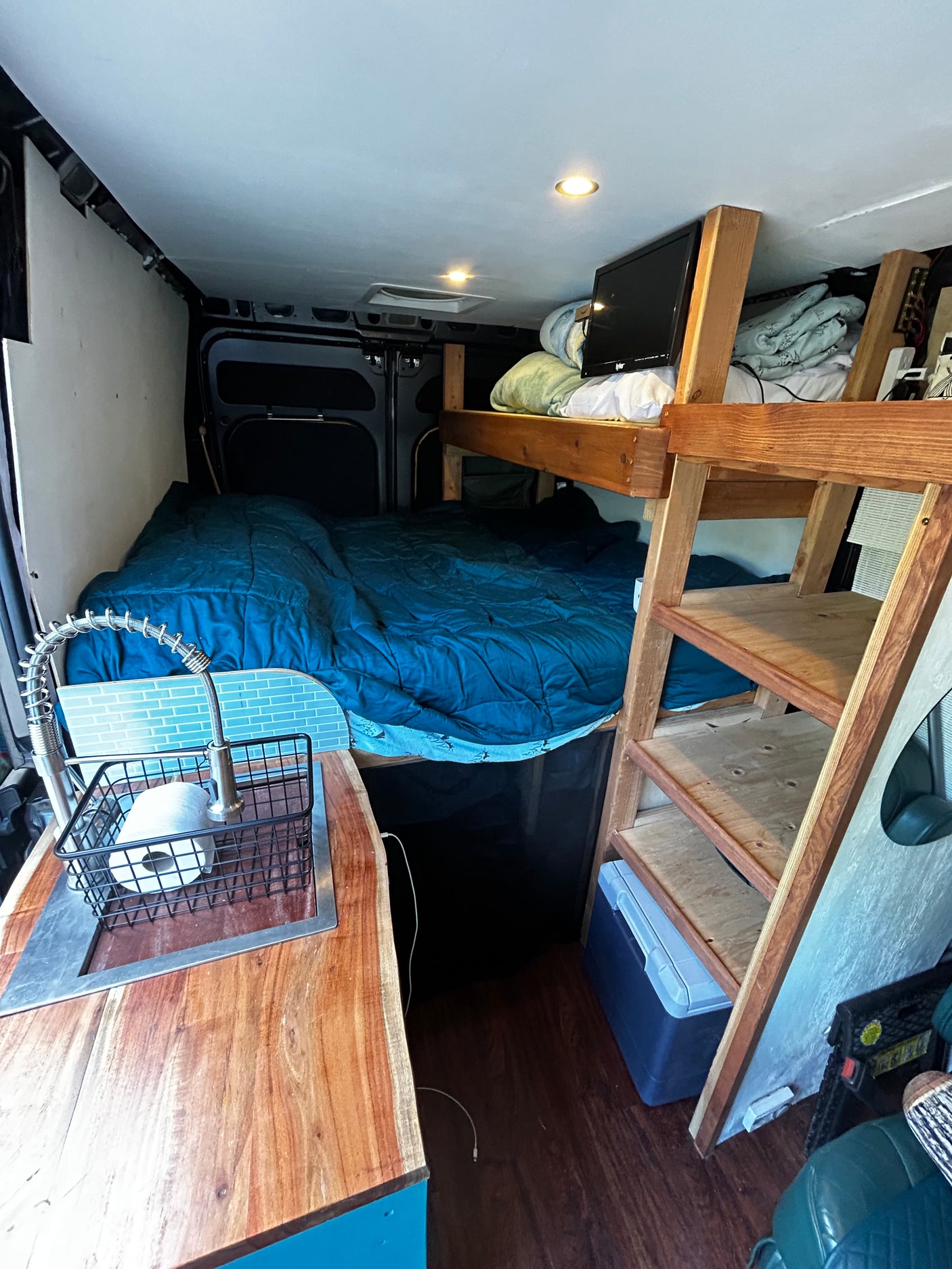 Explore this RV rental's clever interior: a cozy bed, kitchen sink, and overhead bunk for compact living on the go.