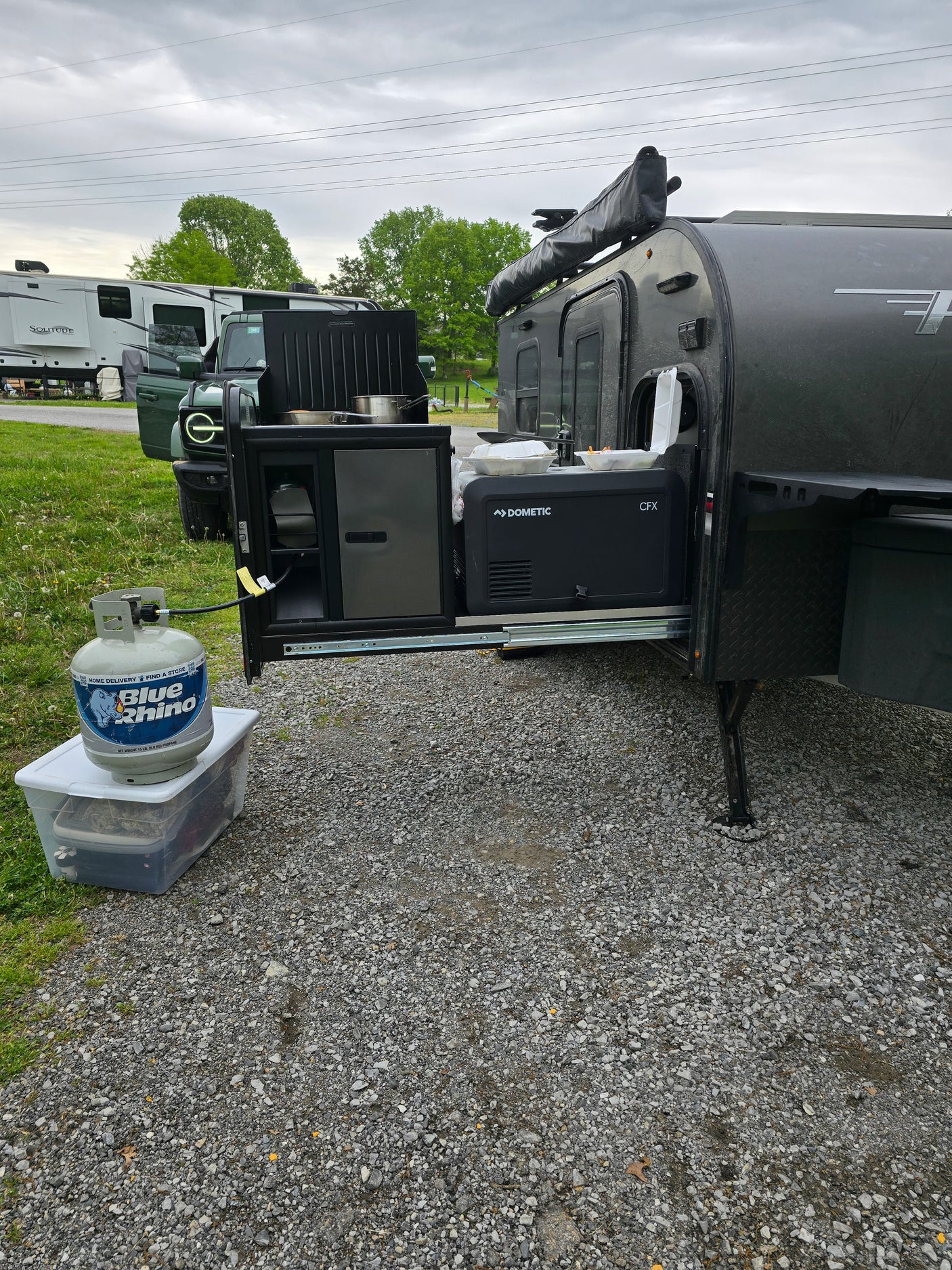 This RV rental features a pull-out outdoor kitchen with a Dometic cooler and a Blue Rhino propane tank, perfect for campsite cooking.