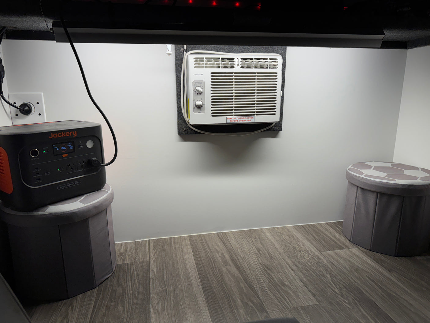 This RV rental interior features a Jackery portable power station, a Frigidaire AC unit, and storage stools, for compact living.