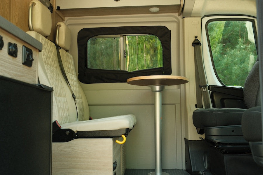 RV rental interior: cozy dinette area with seating, table, and window view for travel comfort.
