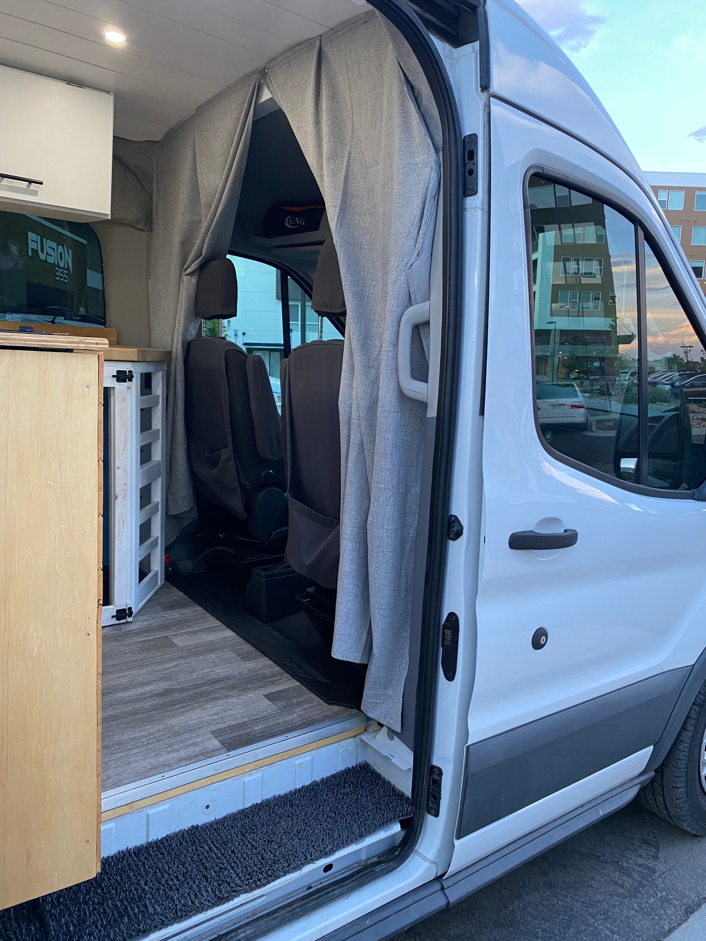 RV rental: Step inside this campervan! Wood flooring, custom cabinets, and privacy curtains create a cozy mobile space.