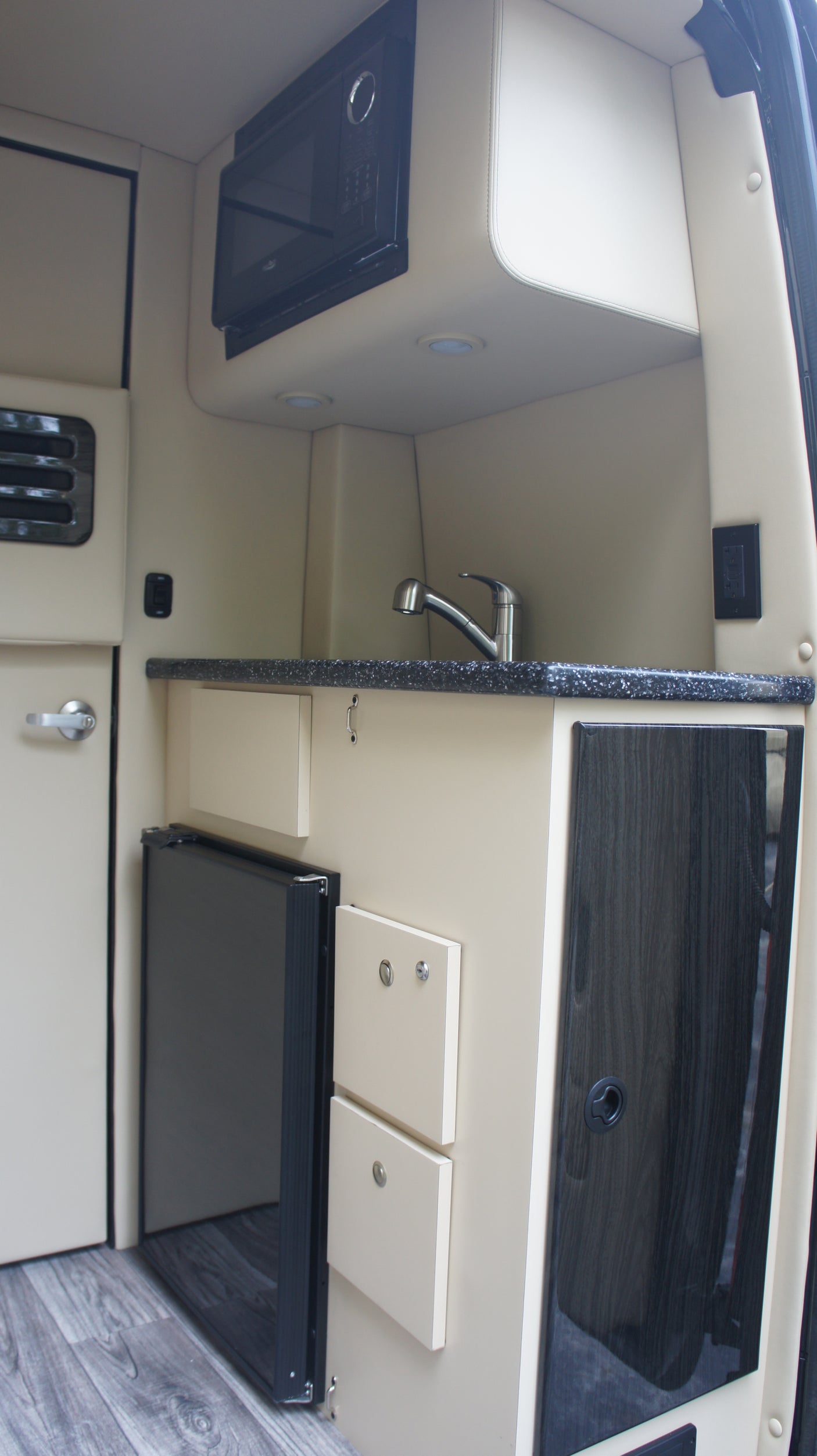 RV rental: Modern kitchenette features microwave, sink, mini-fridge, and sleek storage solutions.