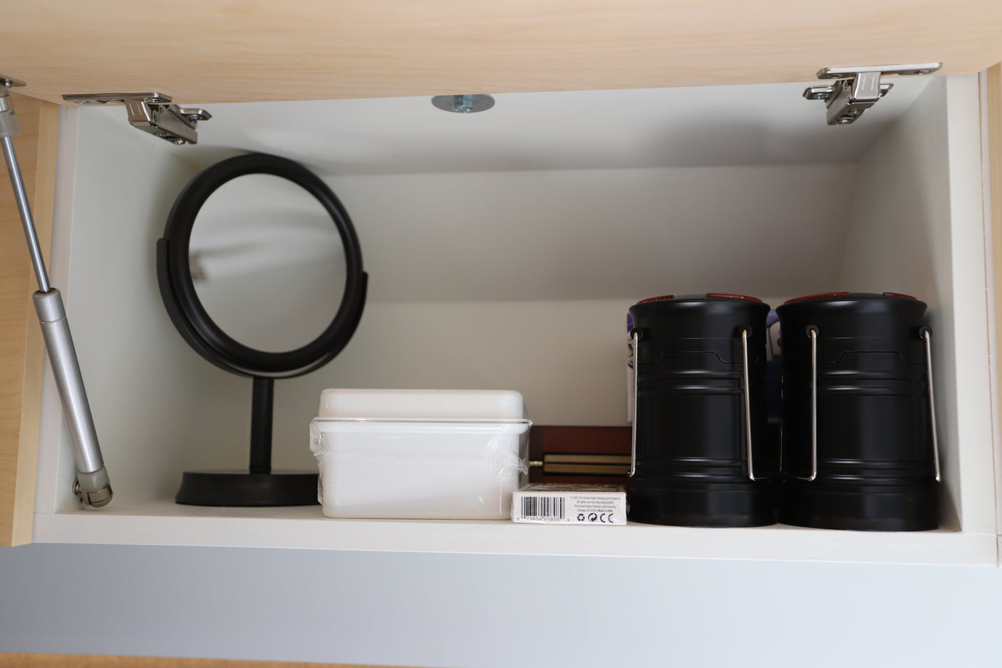 RV rental cabinet essentials: A mirror, playing cards, and camping lanterns for your comfortable journey.