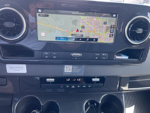 Detailed view of an RV rental dashboard with a navigation screen displaying a map, climate control, and carbon fiber trim.