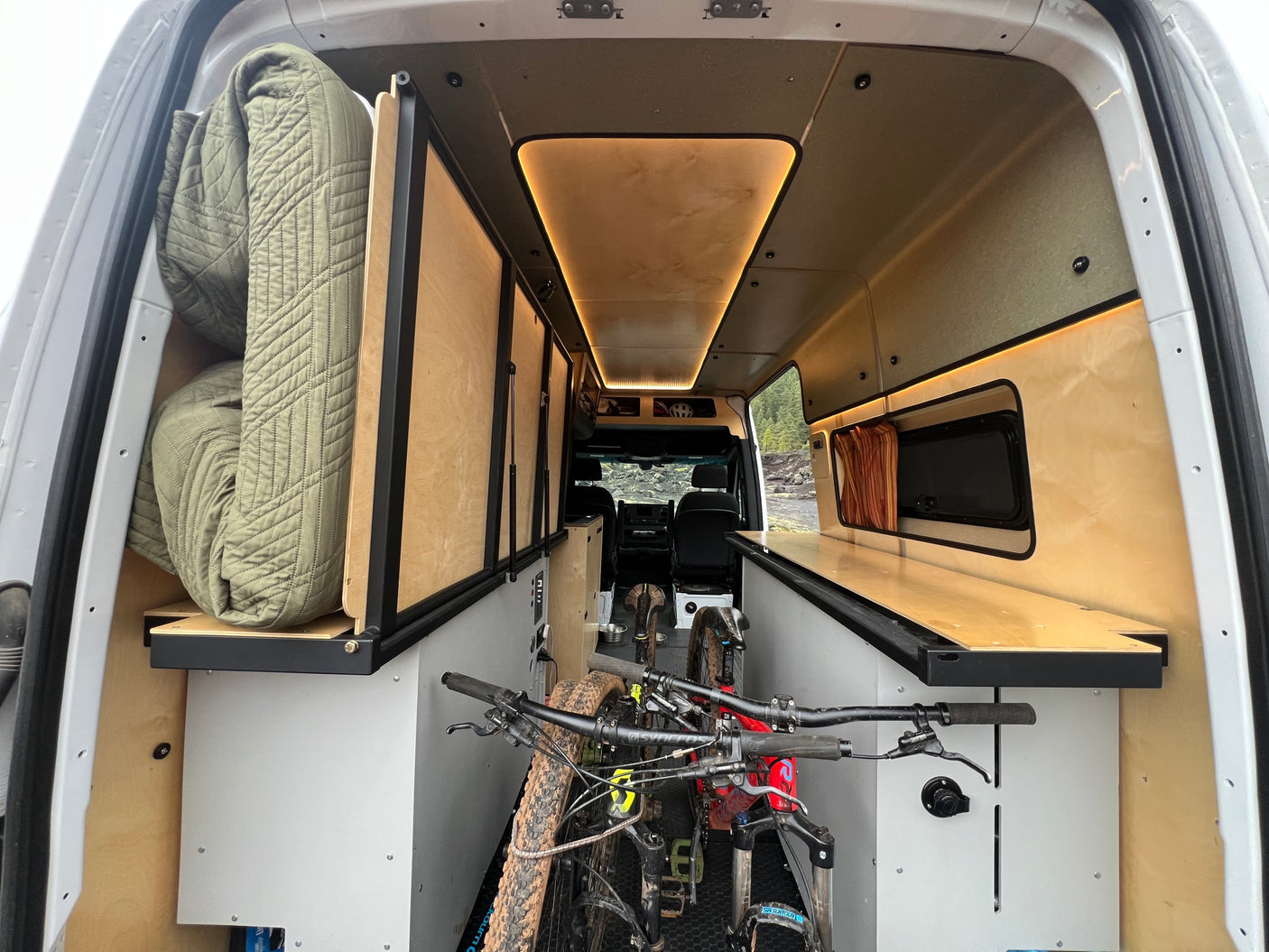 RV rental: Camper van interior with two mountain bikes, built-in storage, wood paneling, and warm lighting. Adventure-ready.