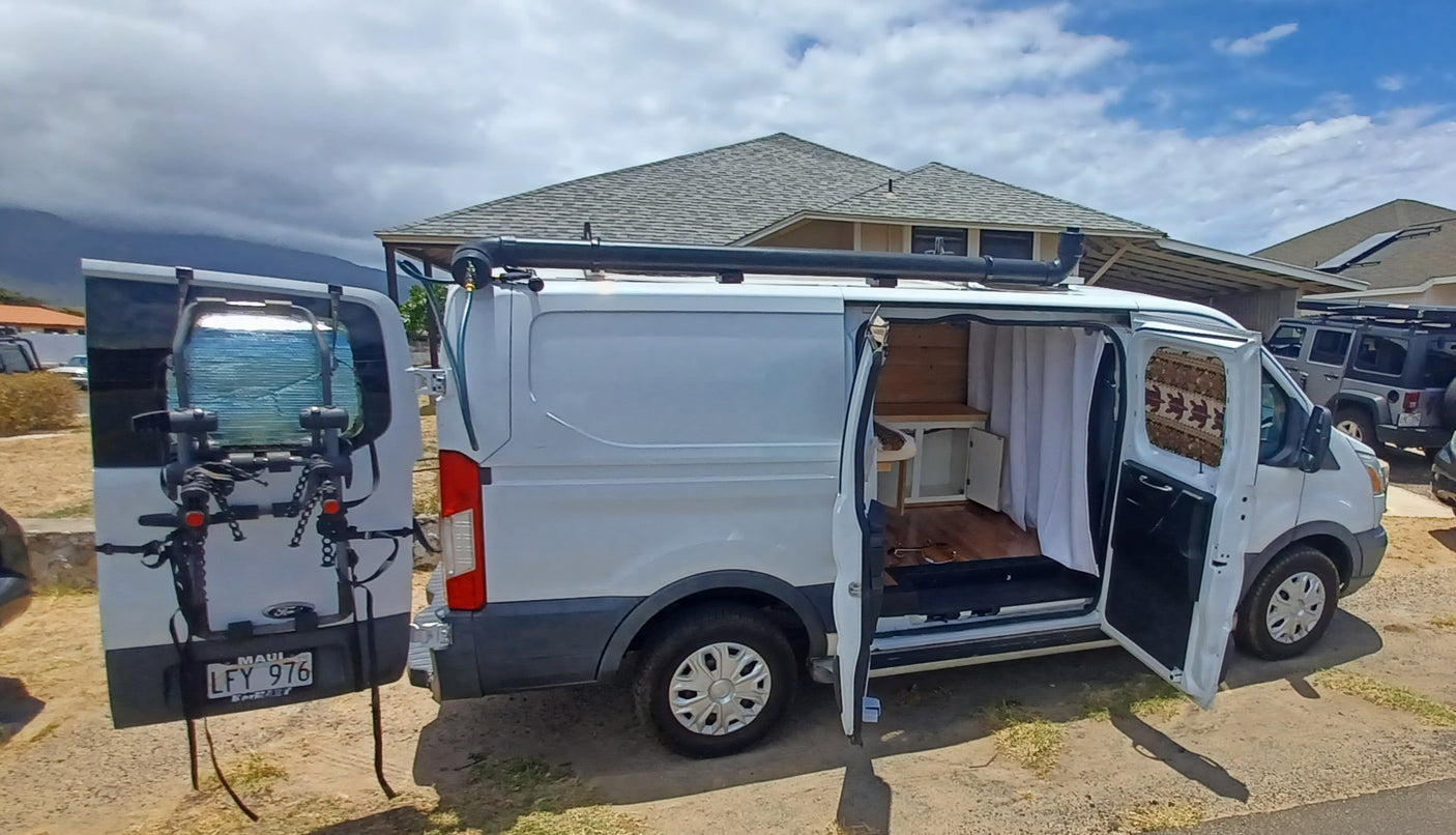 White campervan for rv rental shown with open doors, revealing its cozy, converted interior, ready for travel.