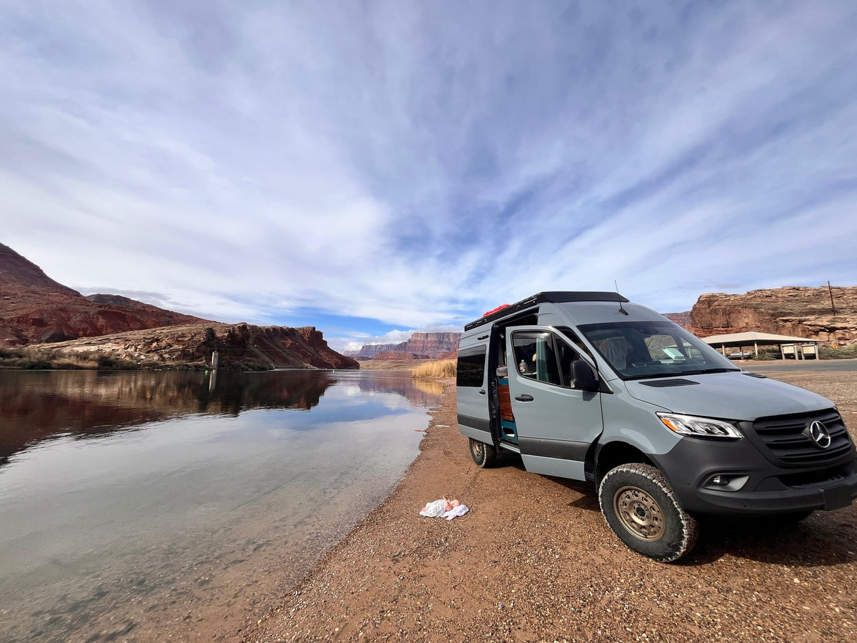 Grey camper van rv rental parked riverside in a stunning red rock canyon — photo 1
