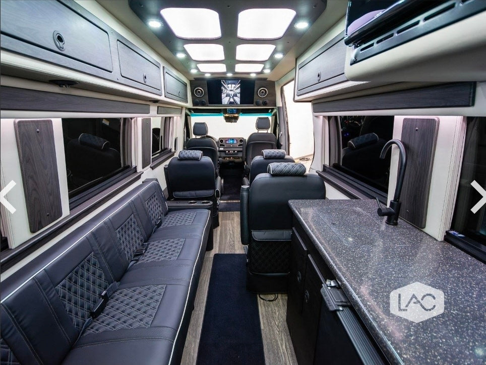 Inside a premium RV rental: comfortable seating, kitchen counter with sink, overhead storage, and TV. Ready for your adventure.
