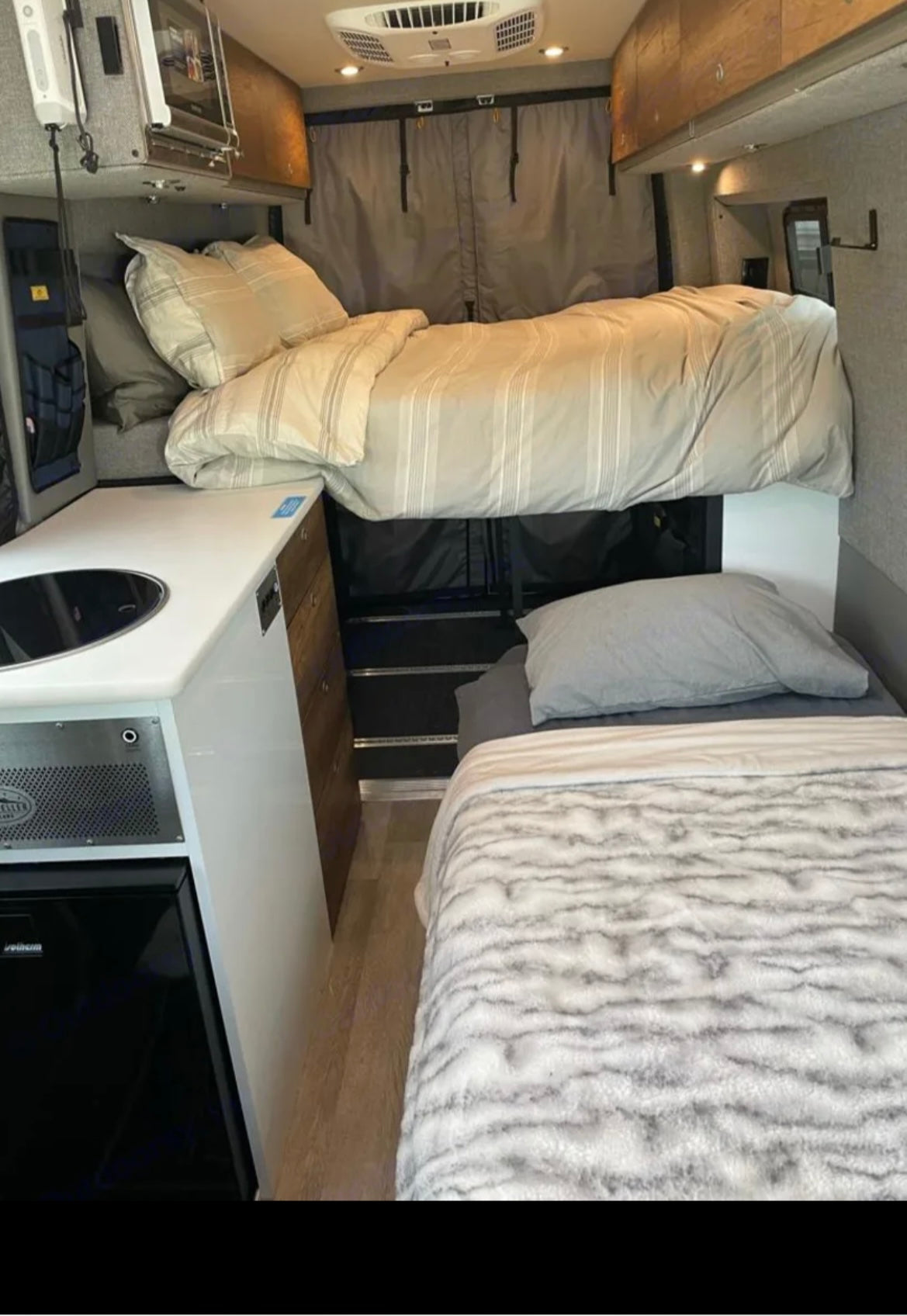 This RV rental features a multi-level sleeping area (bunk beds) and a compact kitchenette with a sink & fridge, ideal for travel.
