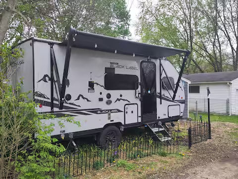 parked for your next adventure.|Modern light gray RV rental with extended awning and steps