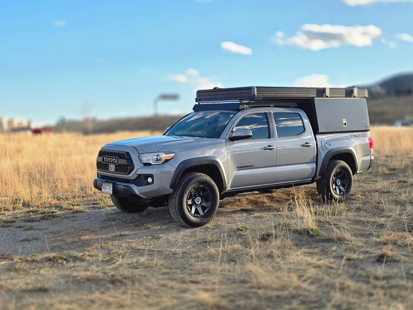 A grey Toyota Tacoma off-road truck with a rooftop tent and camper. Perfect for your next RV rental adventure!