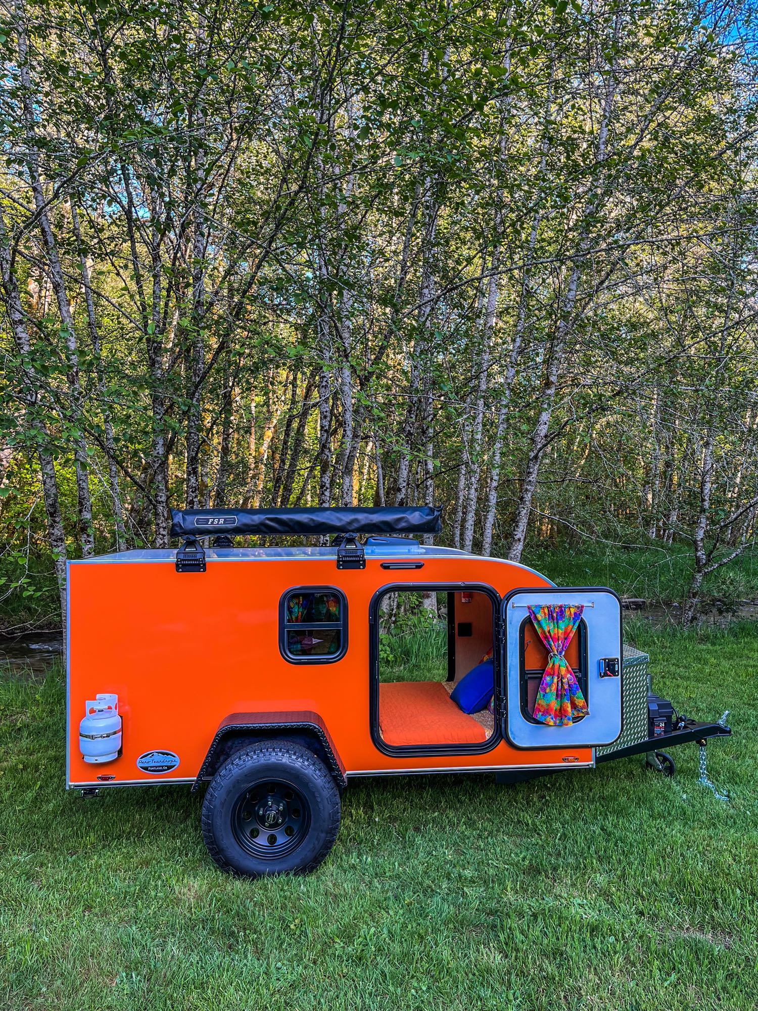 and a scenic forest view out the open door.|A quirky troll doll with straw hair adds character inside this RV rental