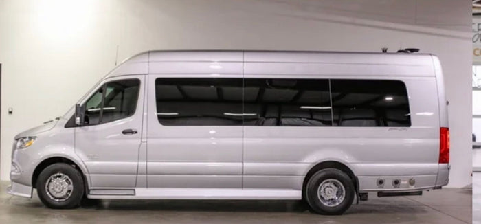 A silver Mercedes Sprinter RV rental. Side profile of a spacious, high-roof camper van in a showroom.