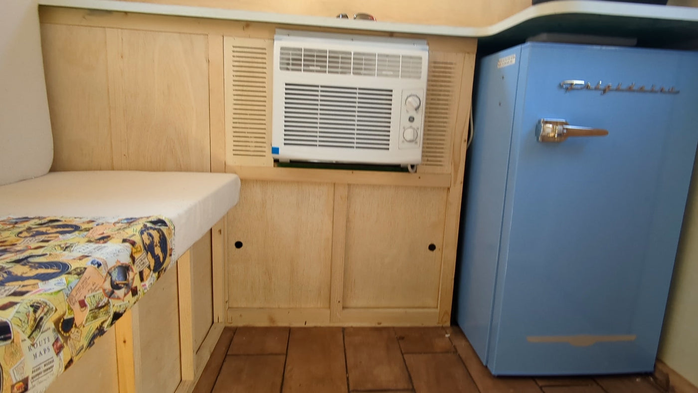 RV rental interior: Built-in AC unit, cozy bench with map cover, and a retro blue mini-fridge for comfortable travel. — photo 6