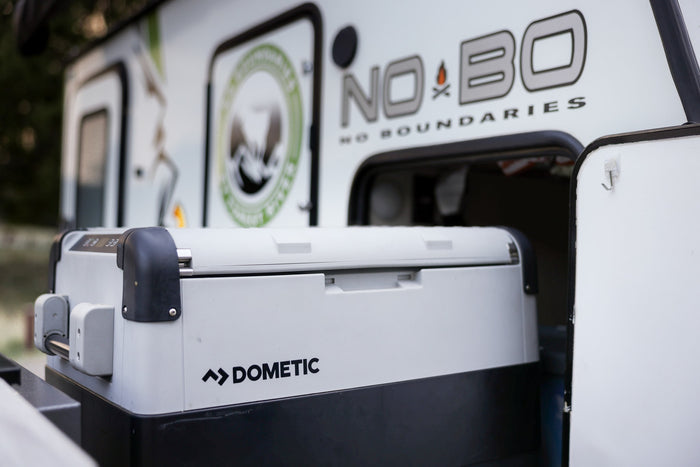ready for adventure.|A Dometic portable fridge in a No Boundaries **rv rental** compartment. Essential outdoor gear for camping adventures!|Inside a cozy RV rental bedroom: bed with a colorful blanket