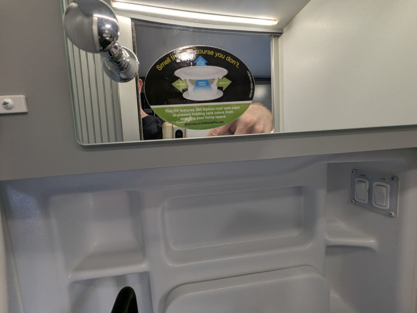 Inside an RV rental bathroom with mirror, shower, and a decal promoting 360 Siphon roof vent caps to prevent holding tank odors. — photo 19