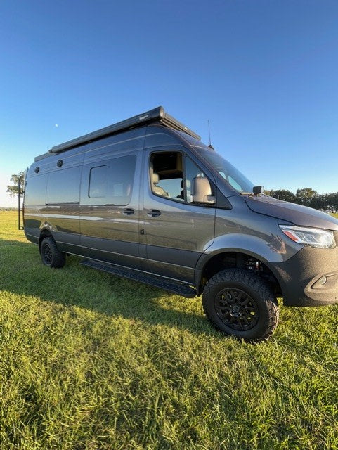off-road Mercedes Sprinter camper van with an awning