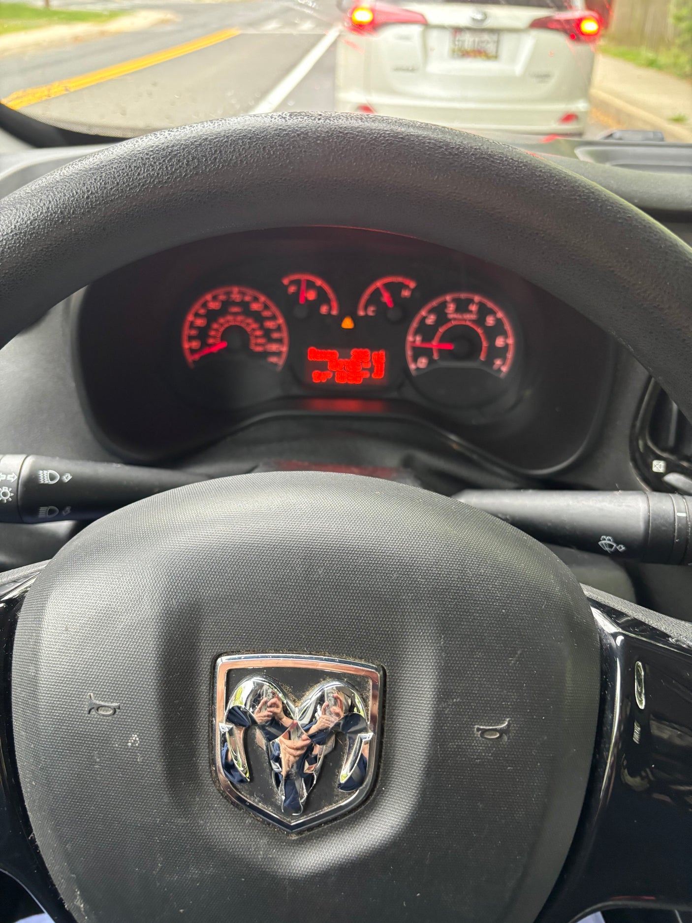 Driver's view in a Ram ProMaster, showing the illuminated dashboard, steering wheel, and road ahead. Explore rv rental options.