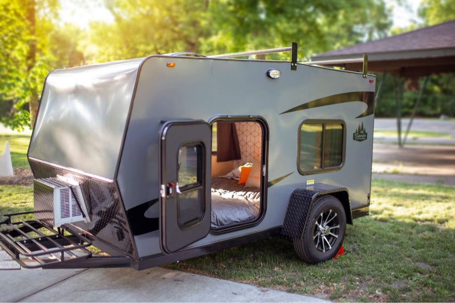 Explore this compact gray RV rental's open door to a cozy bed