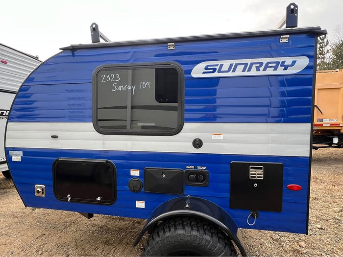 ideal for an rv rental or rugged adventure. Parked near a larger RV.|Blue & gray SunRay teardrop travel trailer