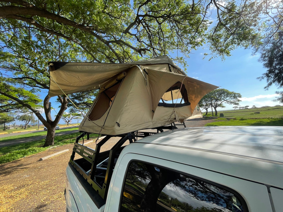 A white pickup truck with an open rooftop tent under lush trees, offering a unique RV rental camping experience. — photo 3